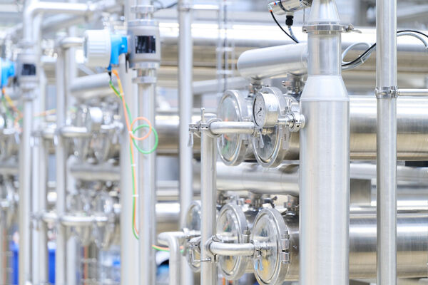 Rows of polished stainless steel pipes, valves and gauges in a food-processing plant