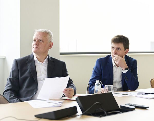 Two colleagues in suits listening attentively at a meeting room table